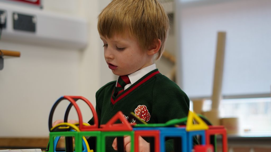 A young boy playing with toys in a classroom.